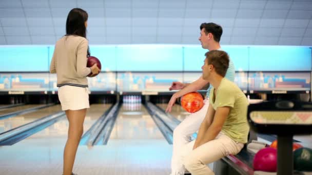 Deux garçons regardent comment la fille fait jeter dans le jeu de bowling — Video