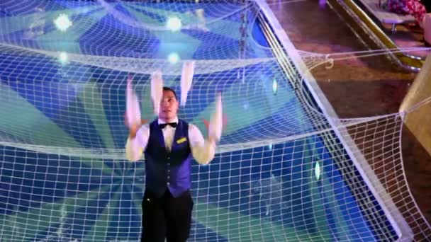 Bartender juggles by four bottles at background of pool with net — Stock Video