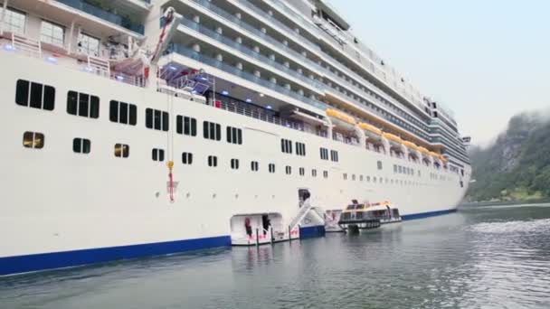 Flotar lejos de enormes pasajeros de línea con barco de rescate en fiordo — Vídeo de stock