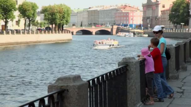 Moeder met kinderen stand op quay en horloge op schip float door rivier — Stockvideo
