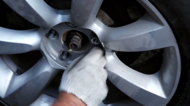 Handen in handschoen schroef opwaarts noten op auto wiel, close-up weergave — Stockvideo