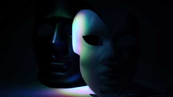 Par de máscaras teatrales en blanco y negro iluminadas por la luz de color — Vídeo de stock