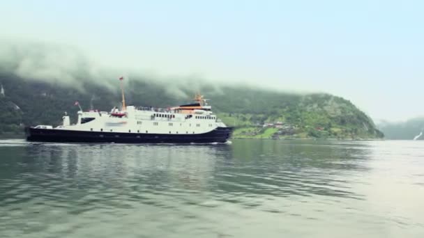 Passengers ship float in fiord at background of coastal village — Stock Video