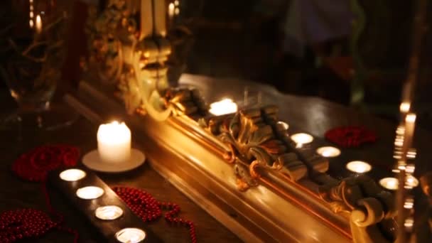 Brennende Kerzen und Perlen vor einem Spiegel in geschnitztem Rahmen — Stockvideo