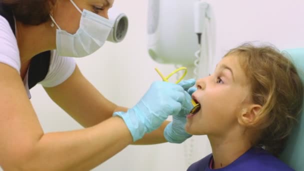 Медсестра кладет специальную тарелку в рот девушке в свинцовом фартуке — стоковое видео