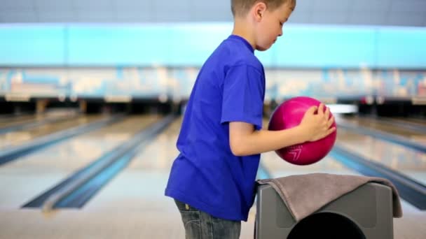Pojken tar bollen och kastar det att slå käglor på bowling lane — Stockvideo
