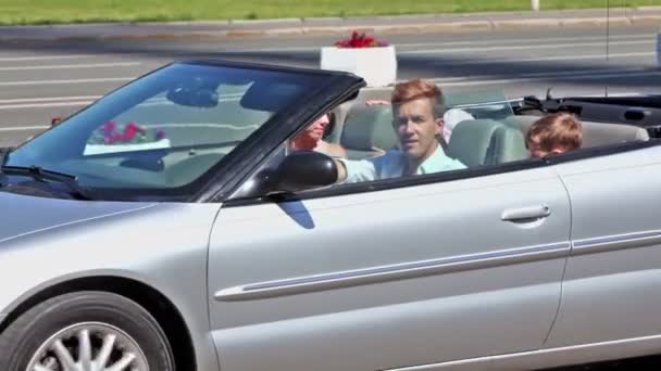 Young couple with two kids pass by in cabriolet — Stock Video