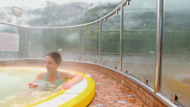 Mujer sonríe en la piscina con agua caliente y vapor cubre todo alrededor — Vídeo de stock