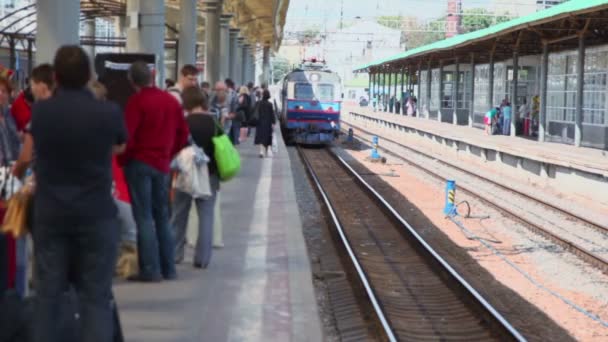 Muitas pessoas esperam pelo trem na plataforma da estação ferroviária — Vídeo de Stock