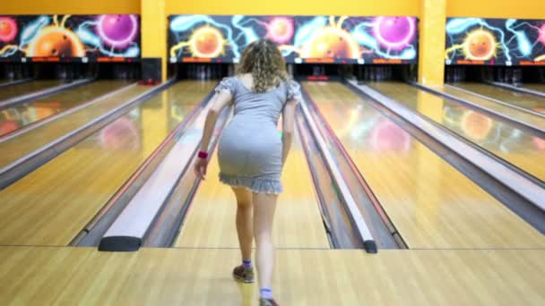 Meisje gooit bowling bal en verslaat alle kegelen — Stockvideo