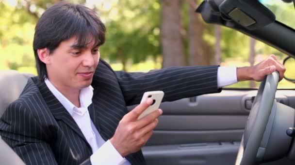 Белый мужчина сидит в кабриолете и разговаривает по телефону в летний день — стоковое видео