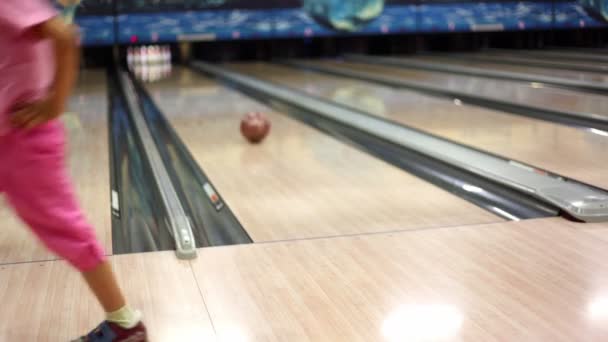 Little girl in pink clothes throws bowling ball and walks away — Stock Video