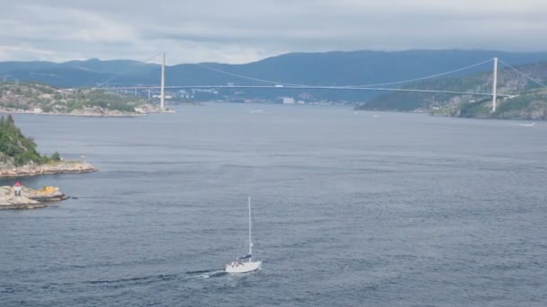 Yacht sail in bay with huge pendant bridge and town at coast — Stock Video