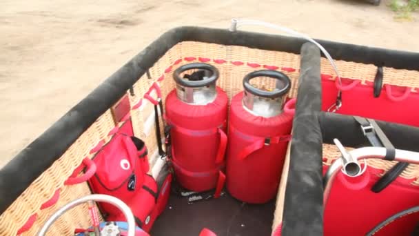 Two red cylinders with gas stand in balloon basket — Stock Video