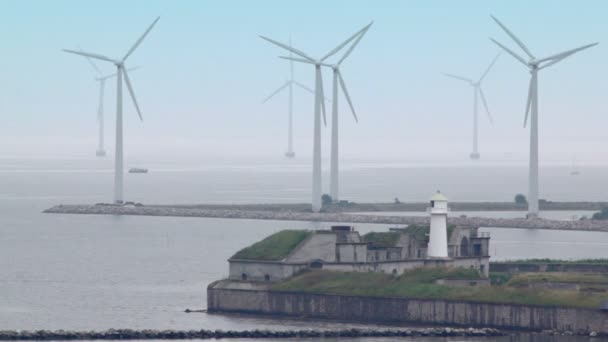 Faro en la orilla y molinos de viento que producen electricidad — Vídeos de Stock