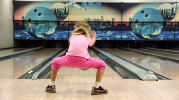 Liten flicka i rosa kläder kastar bowlingklot och flyr — Stockvideo