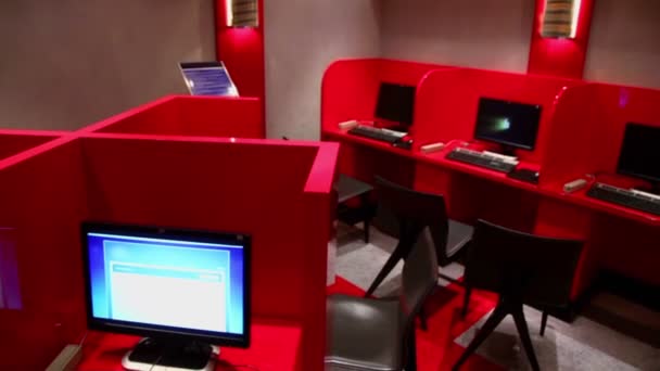 Mehrere Arbeitsplätze in leerem Internetcafé mit roten Trennwänden — Stockvideo