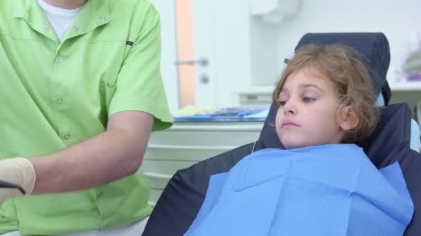 El dentista toma la herramienta de succión de saliva, luego pule los dientes de las niñas — Vídeo de stock