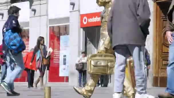 Touristen spazieren auf dem Platz Puerta del Sol in der Nähe einer lebenden Goldstatue — Stockvideo