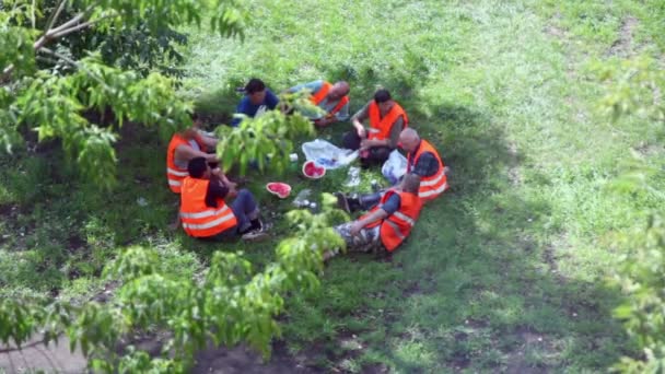 Groep van werknemers in uniforme zitten in ring op picnic op gras — Stockvideo