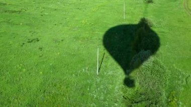 Yüksek balon uçan yeşil çimenlerin üzerinde gölge düşer