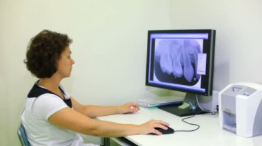 Doktor iş masada oturur ve saatler resmi ekranda x-ışını