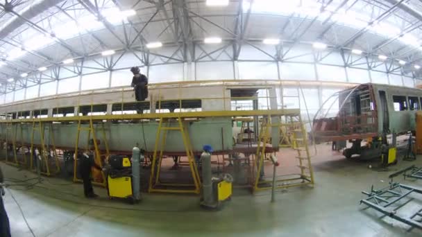 Welder welds roof on carriage in workshop of plant — Stock Video