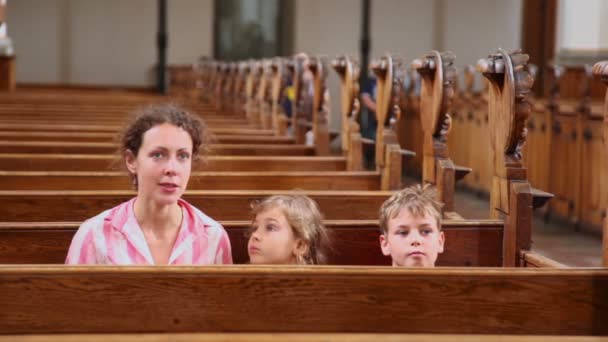 Moeder met twee van haar kinderen zitten op de Bank in de kathedraal — Stockvideo