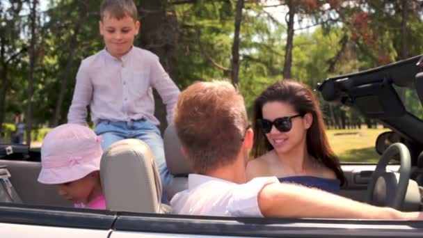 Estudiantes en gafas de sol y dos niños se sientan en cabriolet — Vídeo de stock