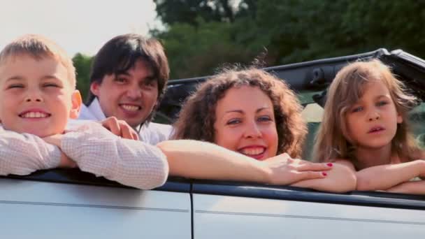 Семья сидит в кабриолете и улыбается в солнечный летний день — стоковое видео