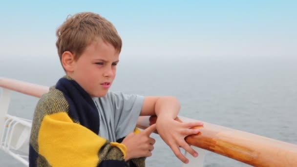 Boy wrapped in plaid stands on deck and admire seascape — Stok video