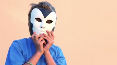 Çocuk maskeleri yüz yakın tutar ve sonra onları bir başka için kaldırır