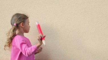 küçük kız duvar üzerine yazmak ve büyük kalem kapağı açar