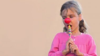 Palyaço burunlu küçük kız yemek renkli şeker ve gülümseme