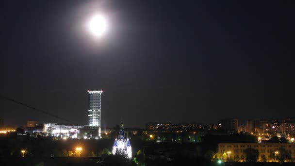 Fullmånen lyser på himlen över natten staden, tidsinställd — Stockvideo