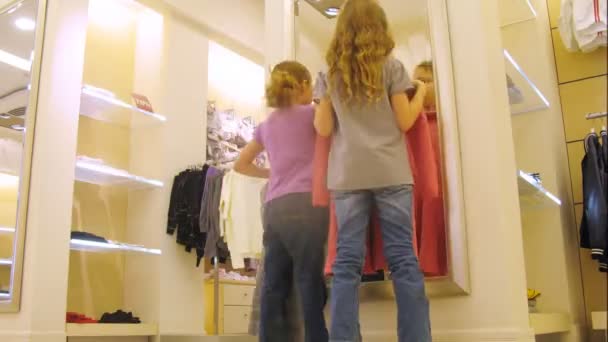 Девушки перед зеркалом примеряют платья в магазине, время истекло — стоковое видео