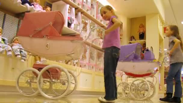 Two girls play with toy carriages for dolls — Stock Video