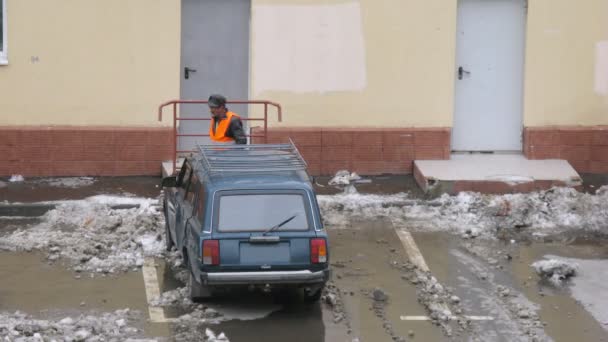 Gastarbeiter räumt Schnee auf Parkplatz für Autos — Stockvideo