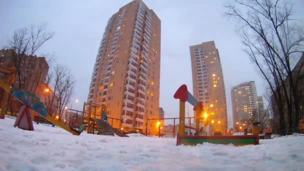 Pojke och flicka spelar med snö i lekplats stan i kväll — Stockvideo