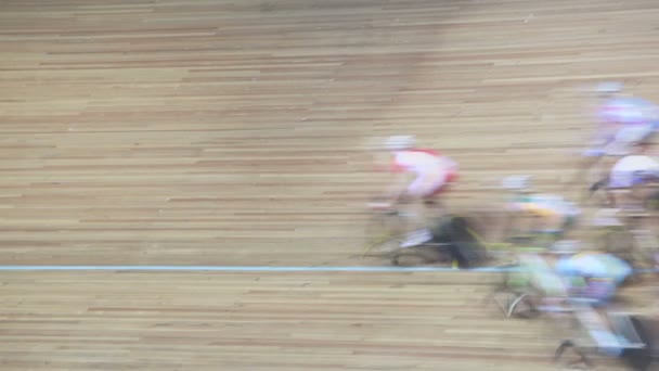 Group of bicyclists pass by track during race in gymnasium — Stock Video