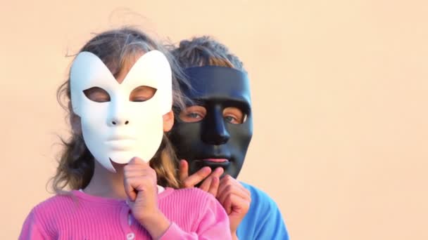 Kinderen houden maskers in de buurt van gezichten en jongen verbergt achter meisje — Stockvideo