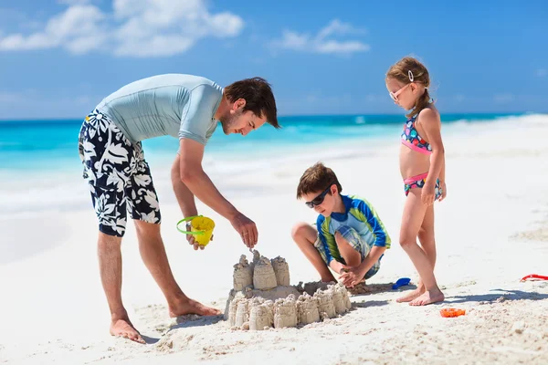 Pai e filhos brincando na praia — Fotografia de Stock