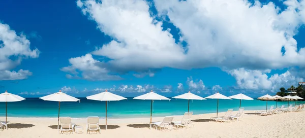 Lehátek a slunečníků na tropické pláži — Stock fotografie