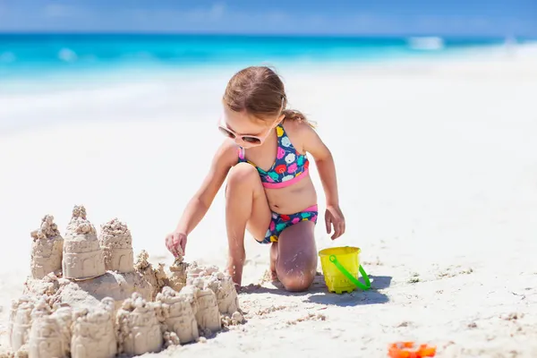 Kleines Mädchen am tropischen Strand baut Sandburg — Stockfoto