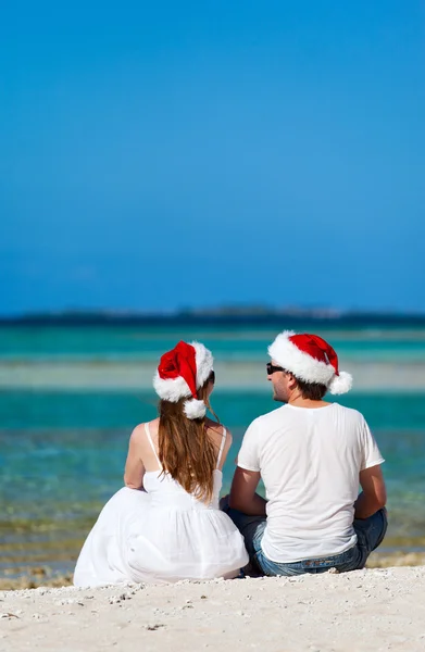 Paar mit Weihnachtsmützen am Strand — Stockfoto