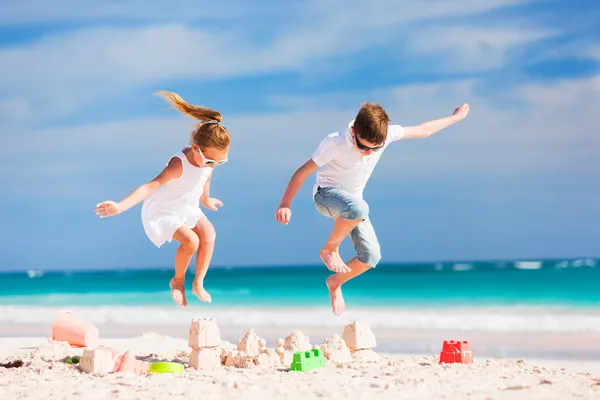 Two kids crushing sandcastle — Stock Photo, Image