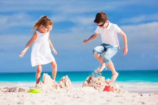 Twee kinderen verpletterende sandcastle — Stockfoto