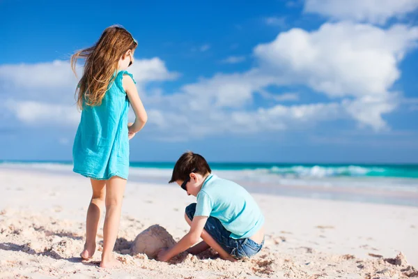 砂で遊ぶ 2 人の子供바위와 바다와 노란 깨끗 한 모래의 투명 한 물의 아름 다운 풍경 — ストック写真