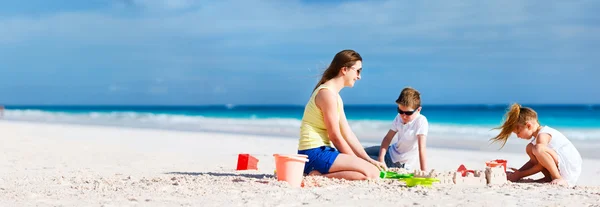 Mutter und Kinder spielen am Strand — Stockfoto