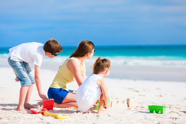 Moeder en kinderen spelen op strand — Stockfoto